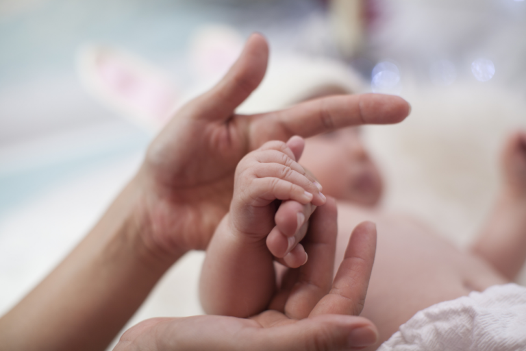 Mom holding newborn's hand after a birth injury